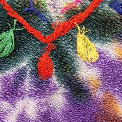 Tecido colorido com pompons e fios entrelaçados em várias cores