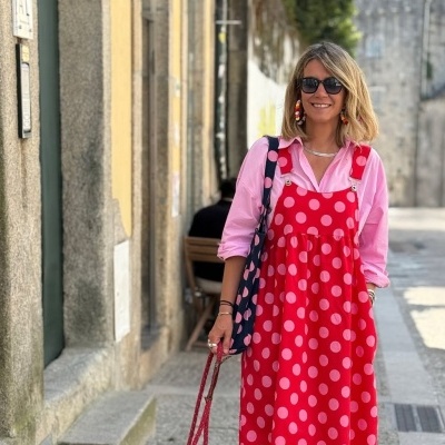 Vestido vermelho com bolinhas cor-de-rosa, camisa rosa, óculos escuros e bolsa azul com bolinhas cor-de-rosa