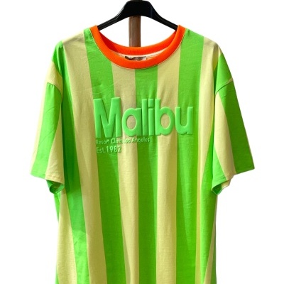 T-shirt riscada verde e amarela com gola laranja e texto kontinente em relevo pendurada numa cabide preta.