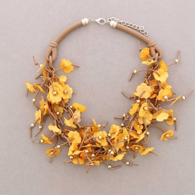 Colar com flores amarelas e castanhas sobre fundo cinza