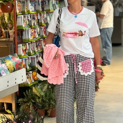 Mulher com t-shirt estampada e calças quadriculadas em mercado floral