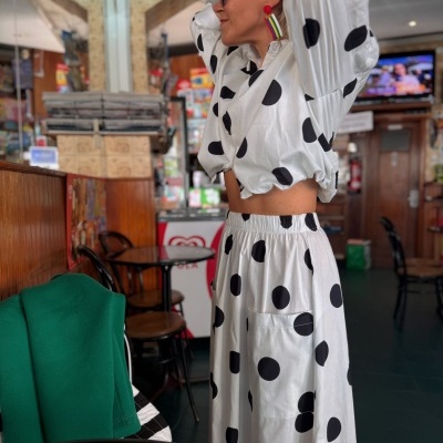 Conjunto feminino branco com bolinhas pretas em ambiente de cafeteria