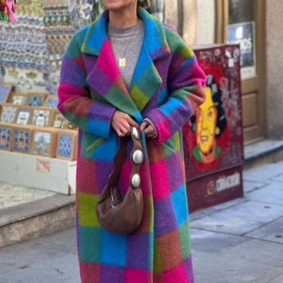 Mulher com casaco colorido e mala castanha na rua