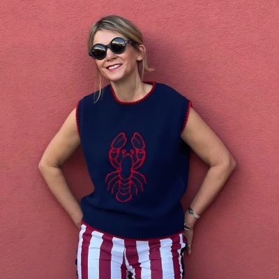 Mulher com camisola azul escura e calças às riscas vermelhas e brancas