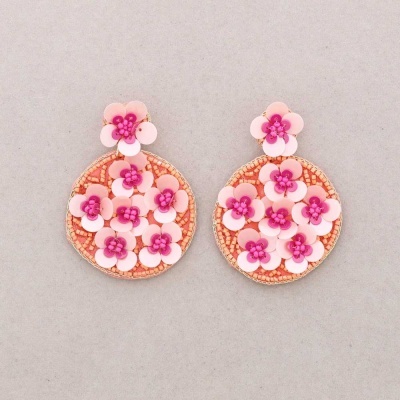 Brincos redondos com flores cor-de-rosa sobre fundo cinza