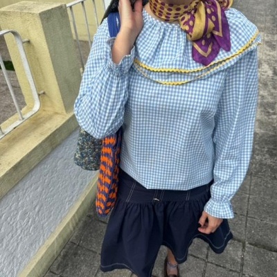 Pessoa com blusa xadrez azul e branca e saia azul escura com acessórios coloridos