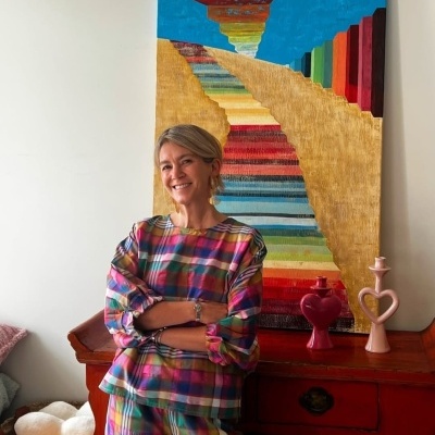 Mulher com roupa xadrez colorida em ambiente com mobília e decoração colorida