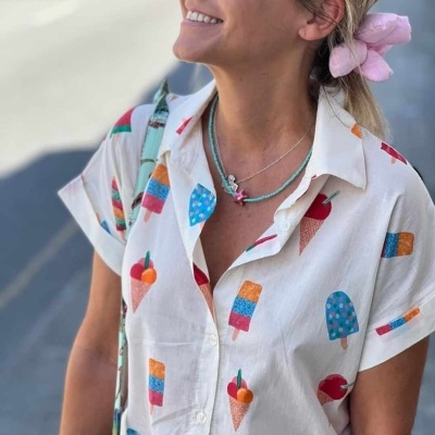 Camisa branca com padrão de gelados coloridos usada por mulher com acessórios e óculos escuros