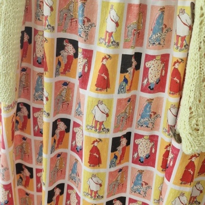 Vestido colorido com padrão de ilustrações de pessoas e cães em quadrados coloridos