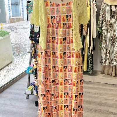 Vestido comprido colorido com padrão de mulheres ilustradas e camisa amarela clara numa loja