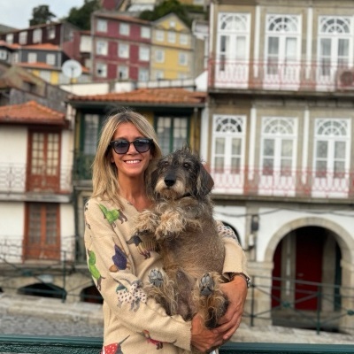 Mulher com camisola estampada a segurar cão castanho e cinzento em área urbana histórica