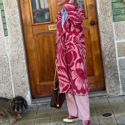 Mulher com casaco rosa e vermelho com padrão floral em ambiente urbano