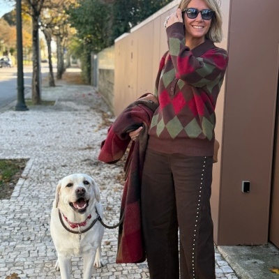 Mulher com camisola argyle colorida e cão labrador num passeio urbano