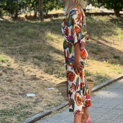 Vestido midi estampado colorido com sandálias rosa de salto alto e bolsa de palha ao ar livre