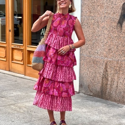 Mulher com vestido rosa vermelho florido e bolsa de crochê multicolor na rua