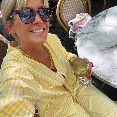 Casaco e calças xadrez amarelo e branco junto a mesa de mármore, bebida no copo.