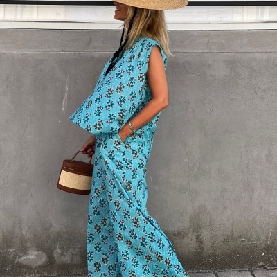 Conjunto azul claro com padrão floral, chapéu de palha, sapatos beges e bolsa redonda castanho e bege