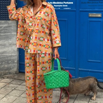 Mulher com roupa colorida e mala verde ao lado de porta azul com texto