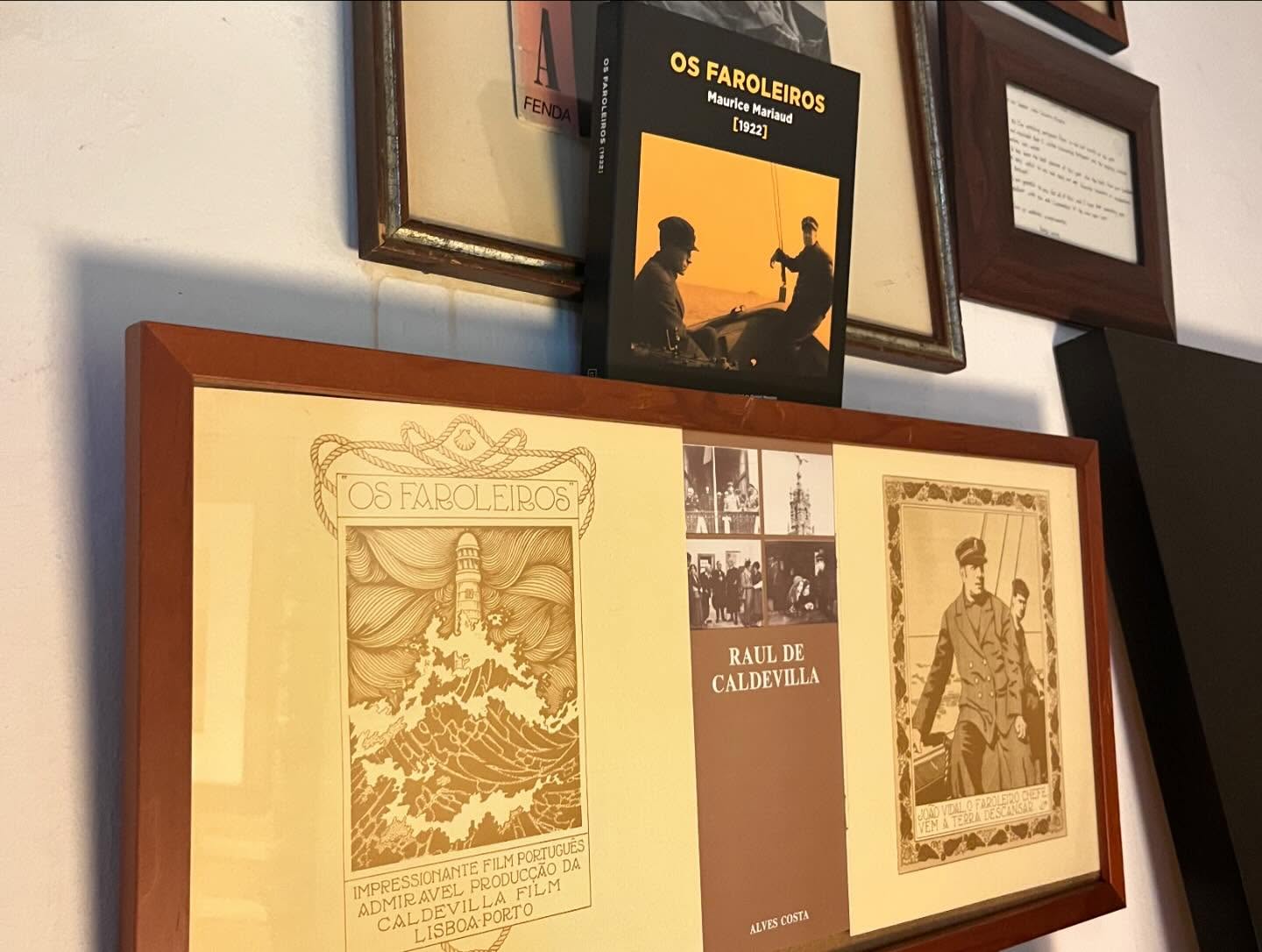 OS FAROLEIROS ∙ MAURICE MARIAUD Livro 'OS FAROLEIROS' encostado na parede com quadros emoldurados em madeira.