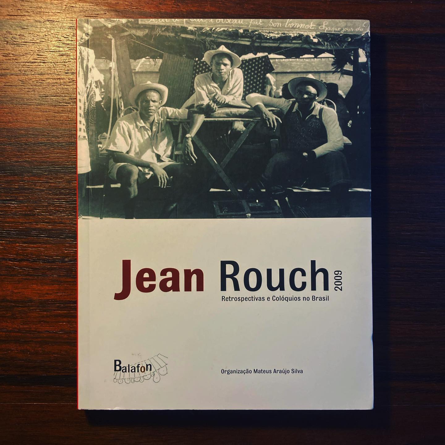 JEAN ROUCH 2009 ∙ RETROSPECTIVAS E COLÓQUIOS NO BRASIL ∙ MATEUS ARAÚJO SILVA (ORG.) Capa de livro branco com foto em preto e branco e texto em vermelho e preto.