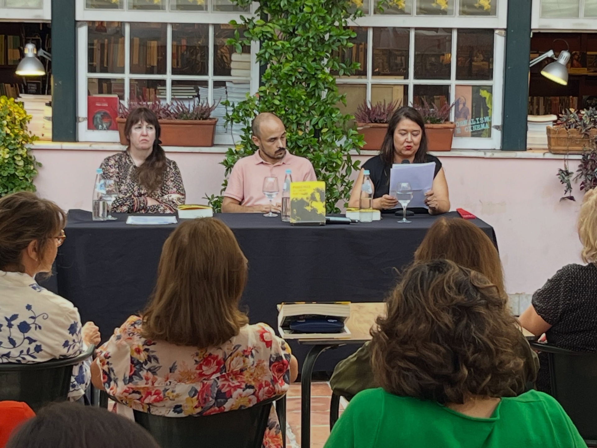 PIONEIRAS DO CINEMA PORTUGUÊS ∙ RICARDO VIEIRA LISBOA (ORG.) Três pessoas sentadas numa mesa com livros, garrafas de água e copos, ao fundo plantas e estantes de livros.