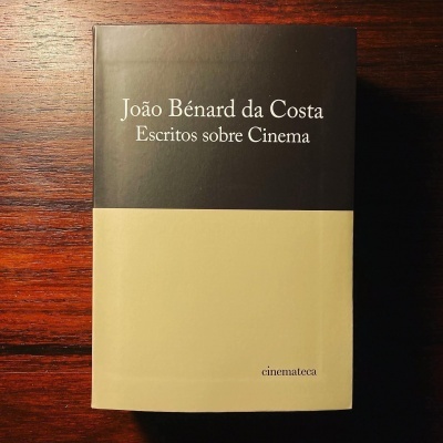 Livro 'João Bénard da Costa Escritos sobre Cinema' com capa preta e bege sobre superfície de madeira.
