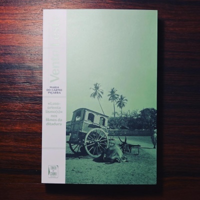 Capa de livro verde com fotografia em preto e branco de carroça, bois e palmeiras sobre mesa de madeira.