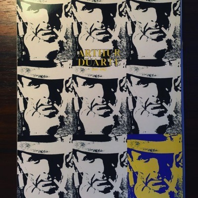 Cartaz pop art com múltiplas imagens de rosto masculino e texto ARTHUR DUARTE