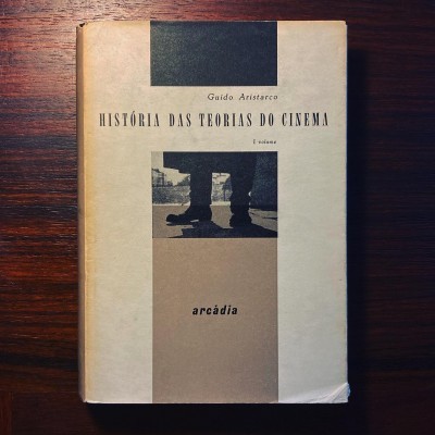 Capa de livro 'História das Teorias do Cinema' sobre mesa de madeira