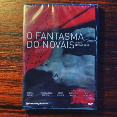 Capa de DVD do filme O Fantasma do Novais com cores vermelha e preta, mostrando homem deitado e desenho de figura masculina com chapéu.