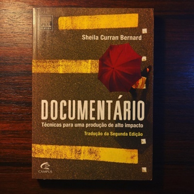 Capa do livro DOCUMENTÁRIO com guarda-chuva vermelho sobre fundo asfáltico. 