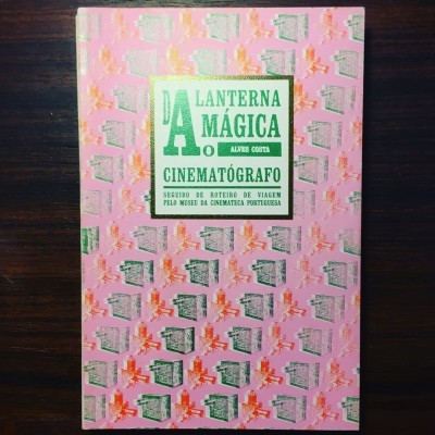 Capa de livro rosa com padrão de lanternas mágicas e texto central em verde e amarelo