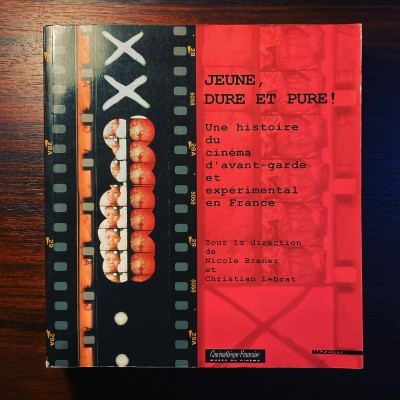 Livro 'JEUNE, DURE ET PURE!' com capa preta e vermelha sobre mesa de madeira