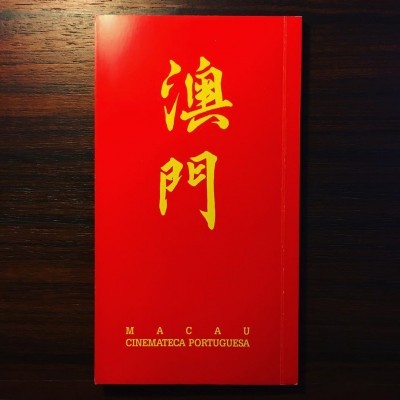 Livro vermelho com texto amarelo sobre madeira escura