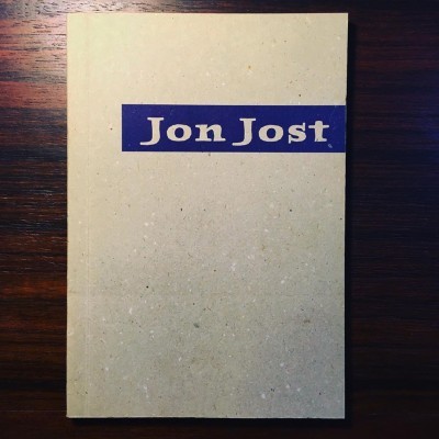 Capa de livro bege reciclado com texto Jon Jost em faixa azul escura