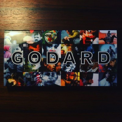 Caixa com mosaico colorido e texto GODARD