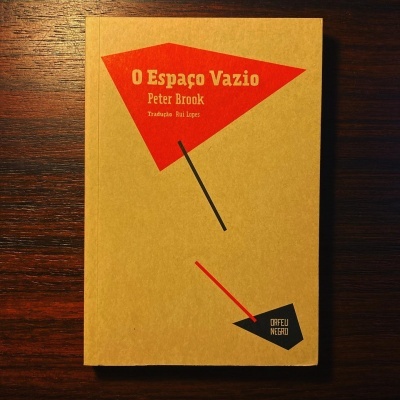 Livro O Espaço Vazio de Peter Brook com capa amarela em superfície de madeira