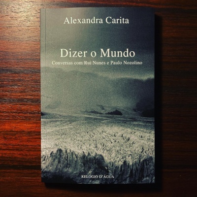 Capa do livro Dizer o Mundo de Alexandra Carita com fundo de paisagem natural em tons escuros