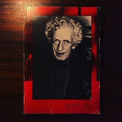 Livro vermelho e preto com foto de homem idoso de cabelo branco encaracolado e assinatura 