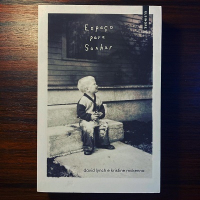 Capa de livro em preto e branco com criança sentada em degrau e texto Espaço para Sonhar