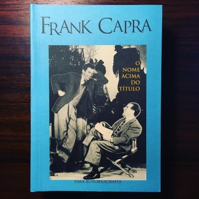 Capa do livro 'O Nome Acima do Título' de Frank Capra num fundo de madeira escura