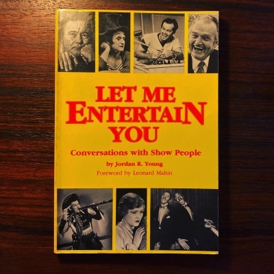 Capa de livro amarela com imagens a preto e branco e título LET ME ENTERTAIN YOU