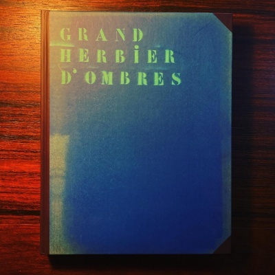 Livro com capa azul escura e cantos em couro castanho com texto dourado