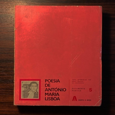 Capa vermelha de livro de poesia com texto e fotografia em preto e branco sobre mesa