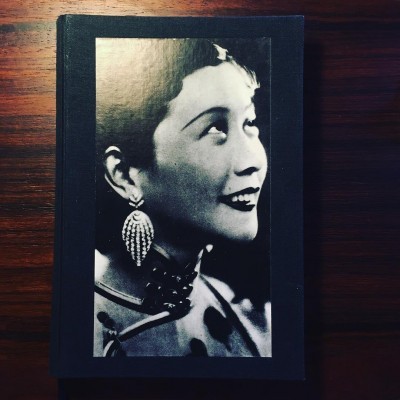 Capa de livro preto com fotografia preto e branco de mulher sorridente com brincos grandes e pérolas