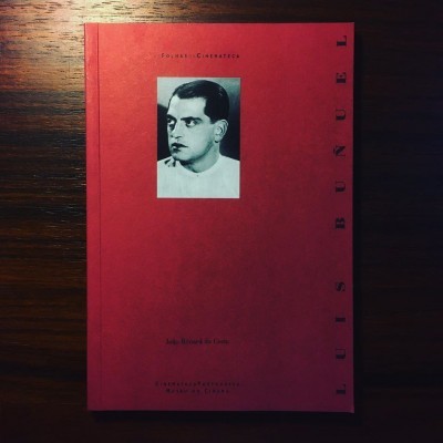 Livro vermelho com fotografia a preto e branco de homem e texto de autoria e título.