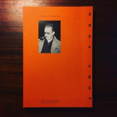 Livro laranja com fotografia a preto e branco de homem e texto 'JOHN FORD' na capa