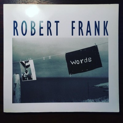 Capa de livro 'ROBERT FRANK' com imagem em preto e branco de tábua e foto penduradas num estendal junto ao mar
