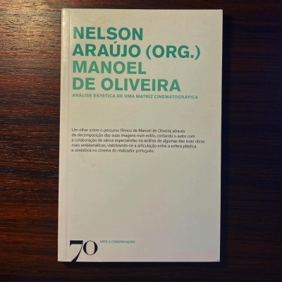 Capa de livro branco com texto verde e preto sobre madeira escura