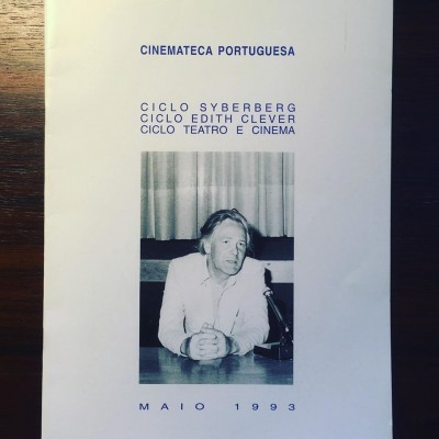 Folheto branco da Cinemateca Portuguesa com texto azul e fotografia a preto e branco